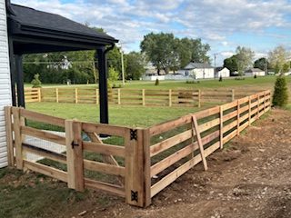 New split-rail wood ranch fence with walk-through gate at the edge of a yard
