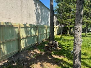 New wood privacy fence built next to an existing brick commercial wall