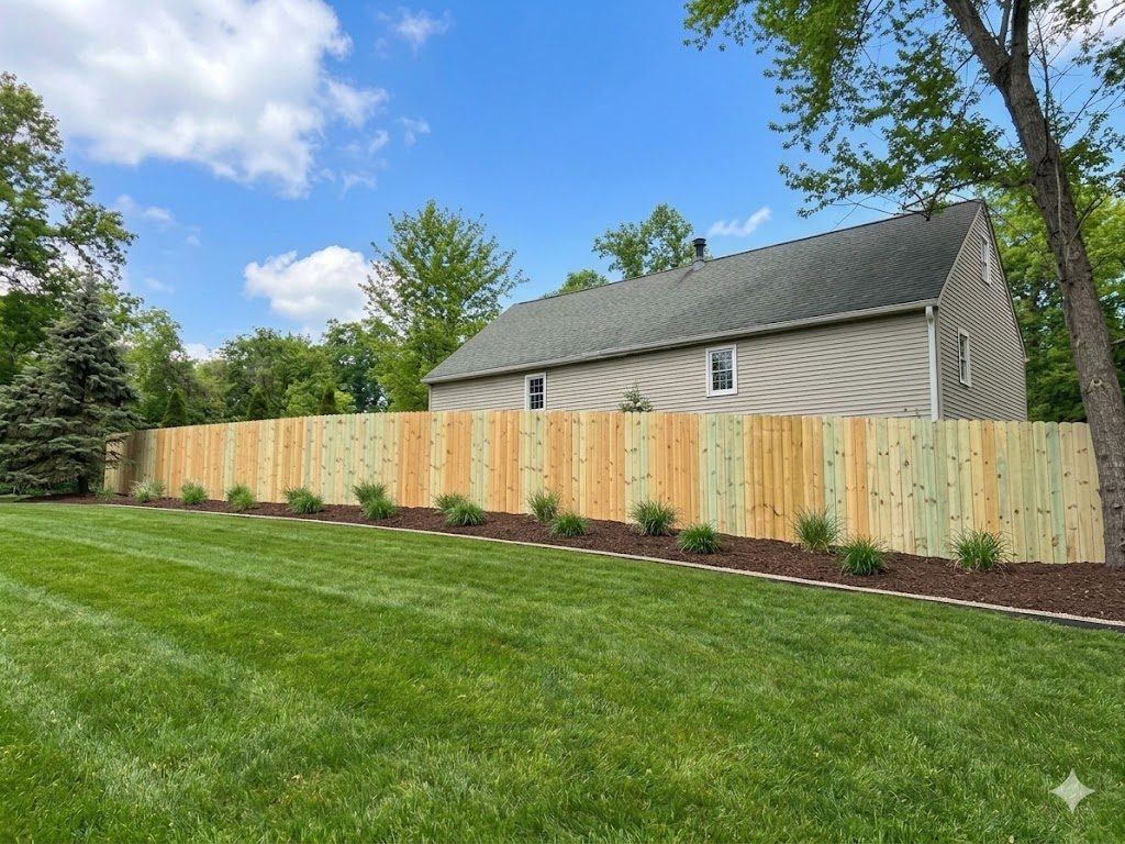 New wood privacy fence wrapping a landscaped backyard with mulched garden beds in Dayton, OH