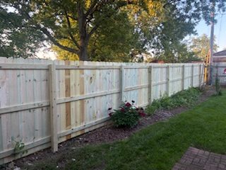 Light cedar privacy fence with a flowering garden bed along the base